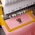 Embroidery machine with a pink fabric and 'LUCKY' design.