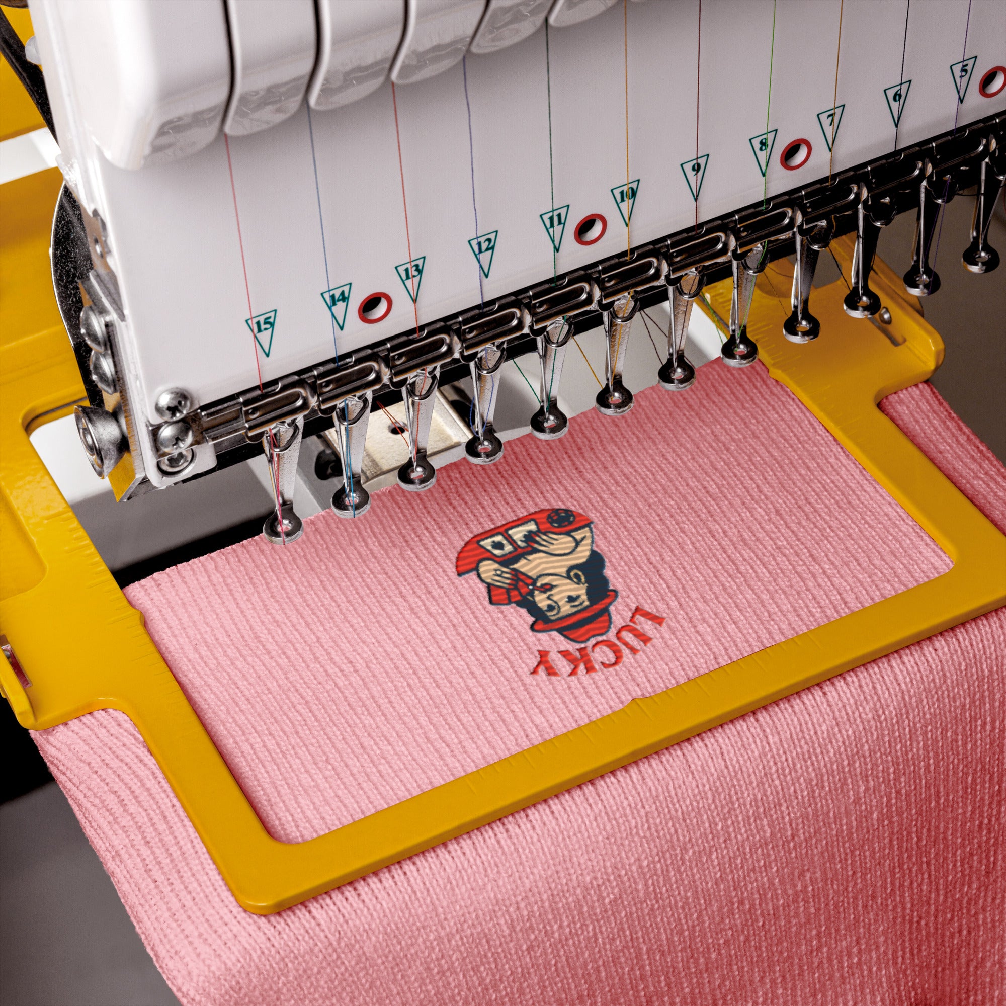 Embroidery machine with a pink fabric and embroidered design on a gray background