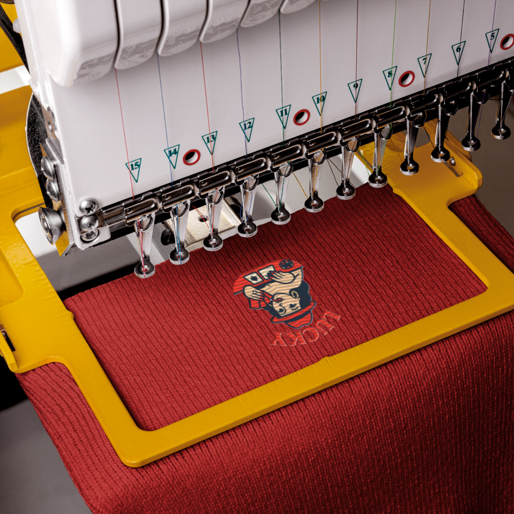 Embroidery machine with a red fabric and logo in progress