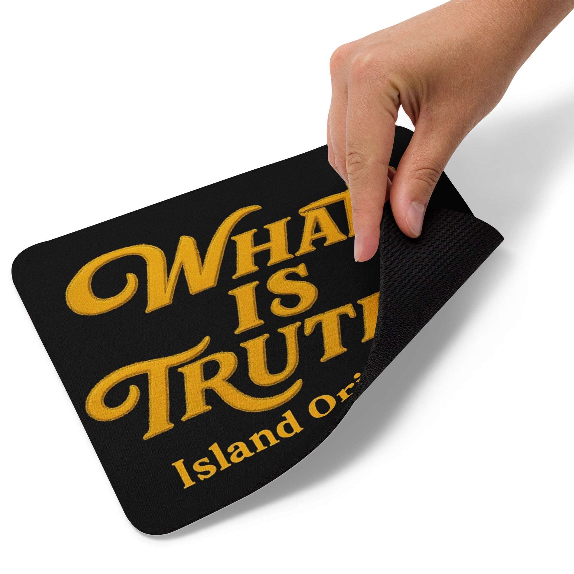 Black mouse pad with yellow text 'WHAT IS TRUTH Island of' held by a hand on a white background