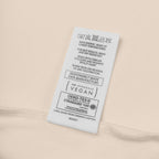 Fabric tag with care instructions and certification logos on a beige background