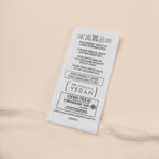 Fabric tag with care instructions and certification logos on a beige background