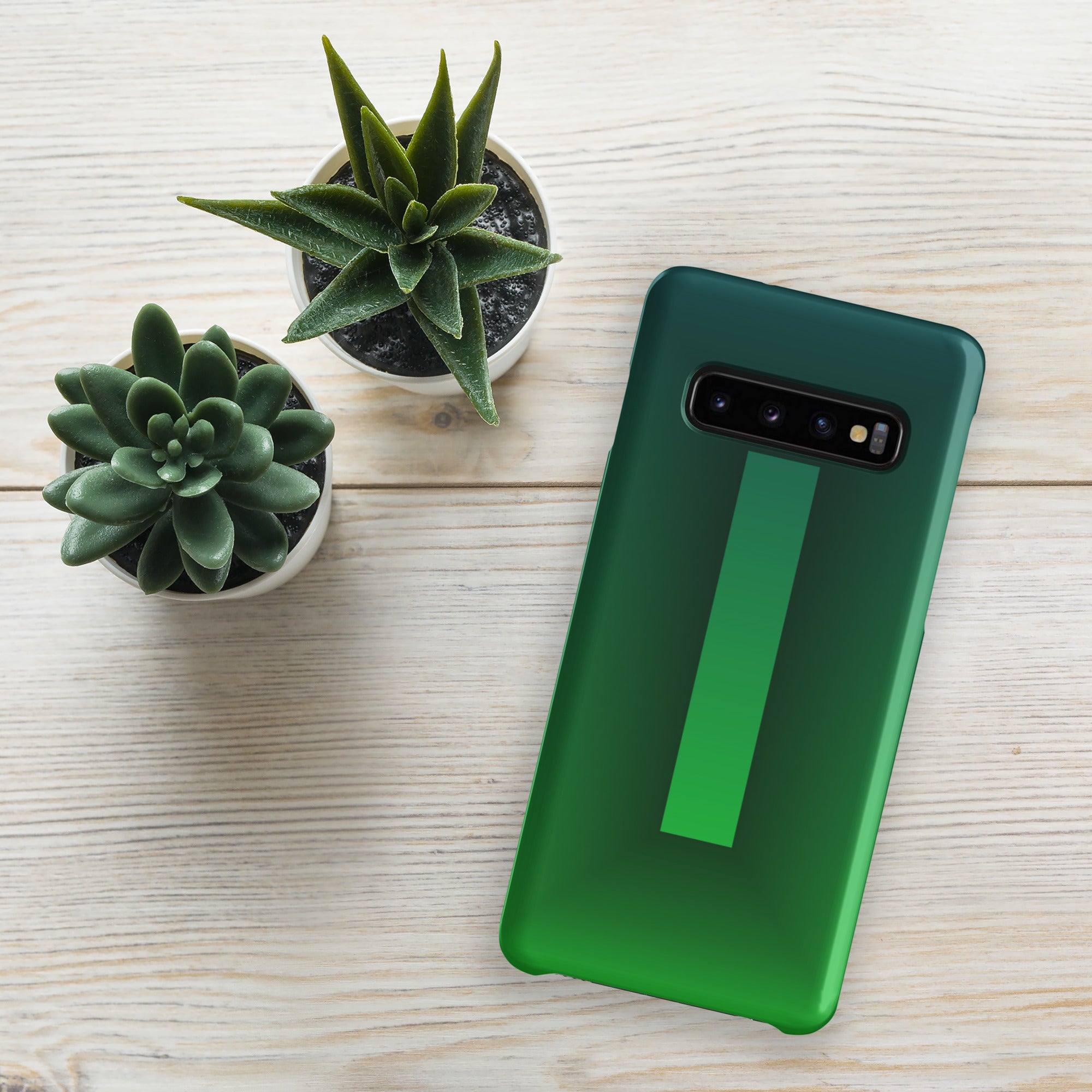 Green phone case on a wooden surface with two small potted plants.