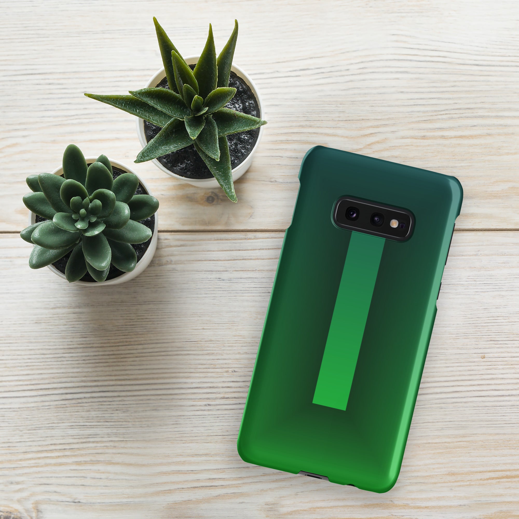 Green phone case on a wooden surface with two small potted plants.