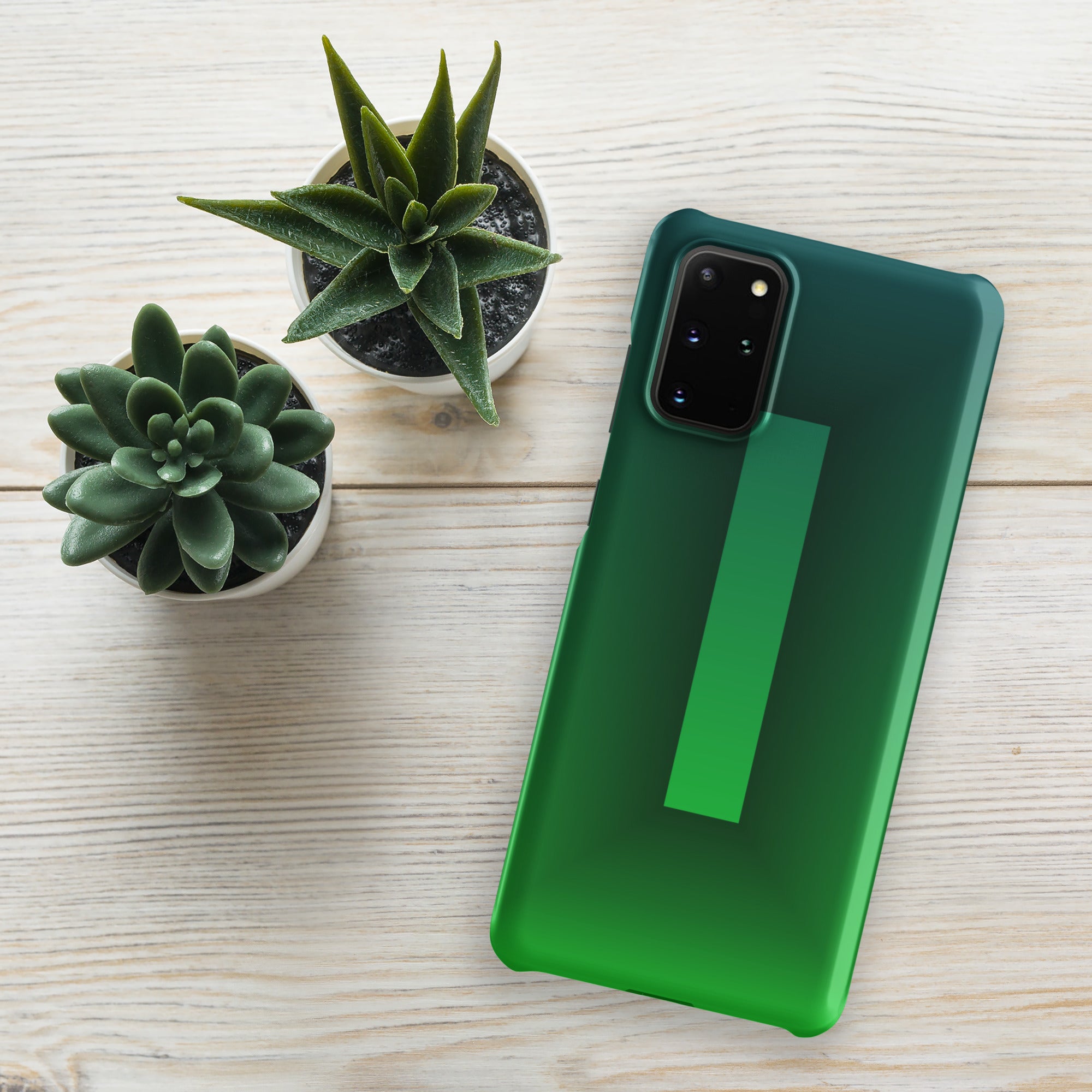 Green phone case on a smartphone with two potted plants on a light wooden surface