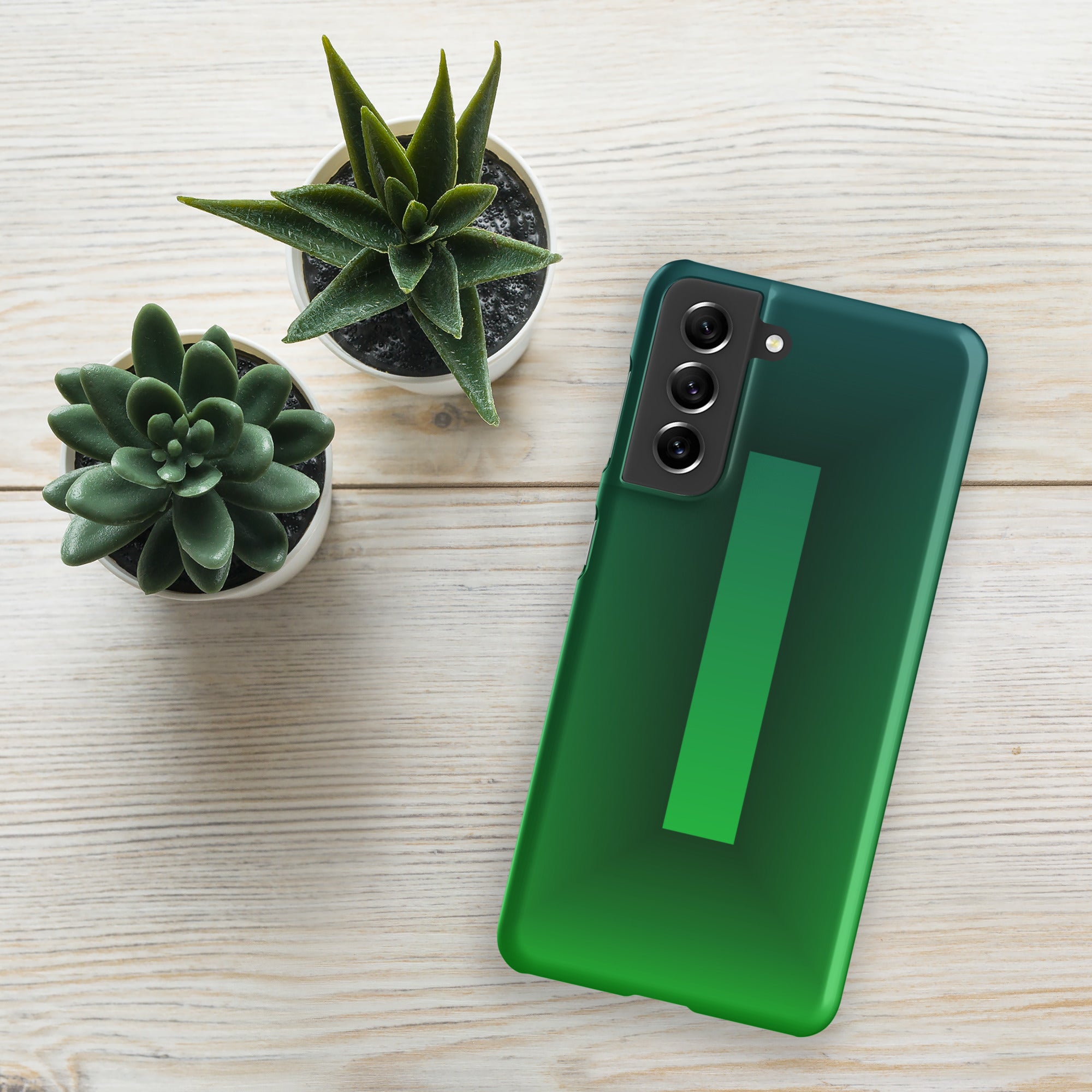 Green phone case on a wooden surface with two small potted plants.