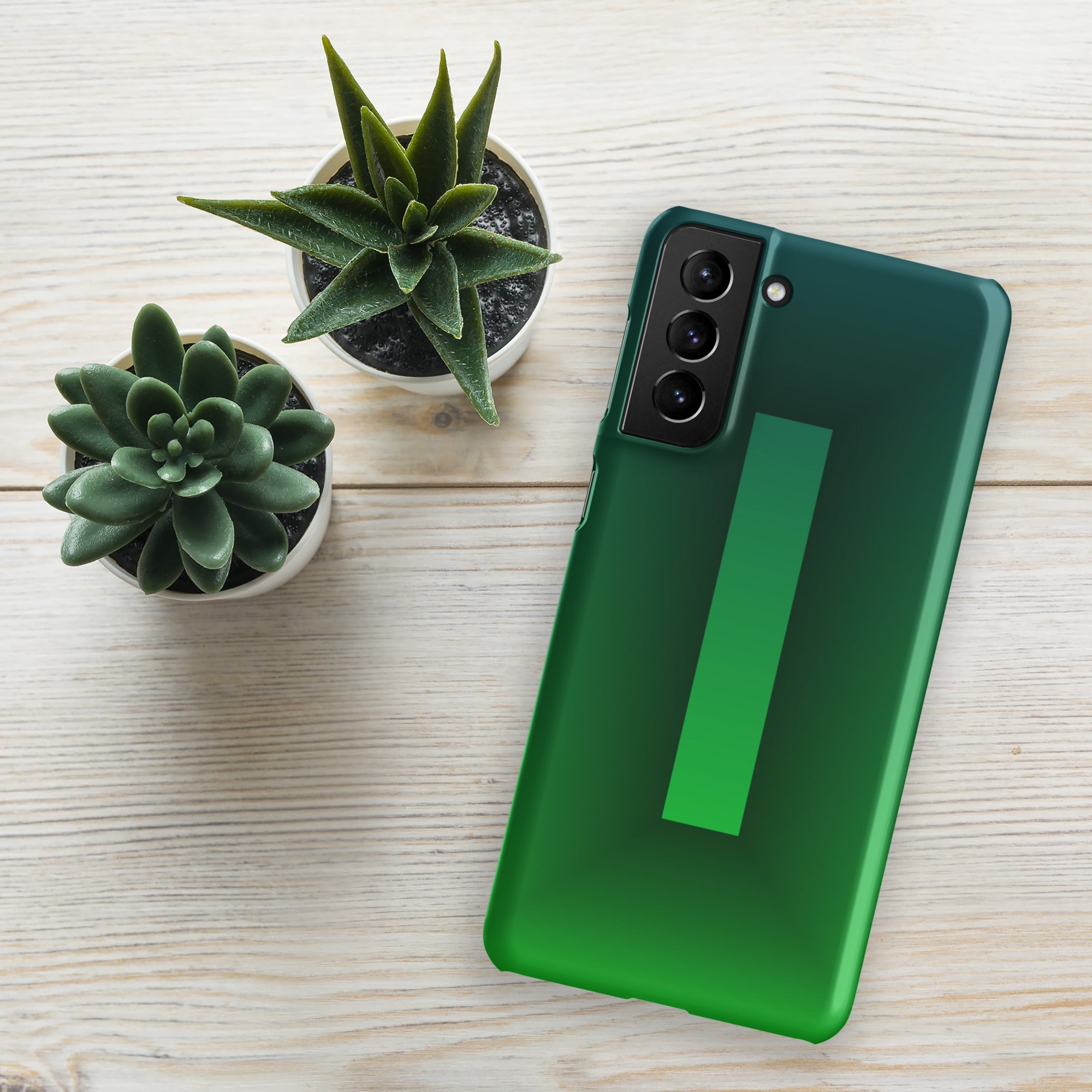 Green smartphone on a light wooden surface with small potted plants.