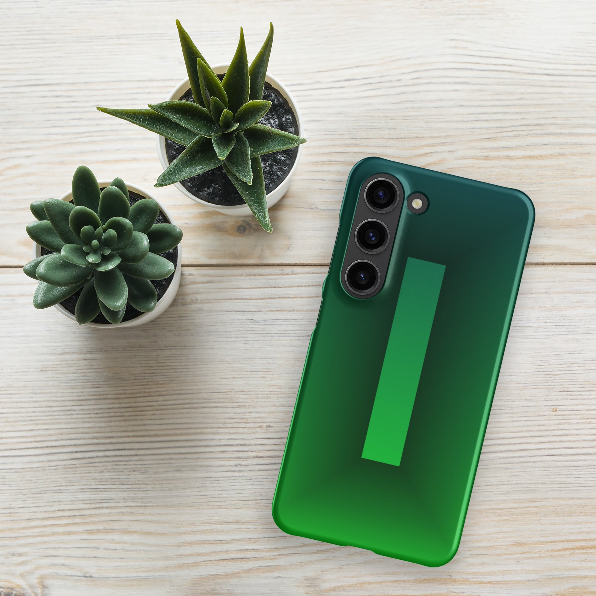 Green smartphone on a wooden surface with two small potted plants.