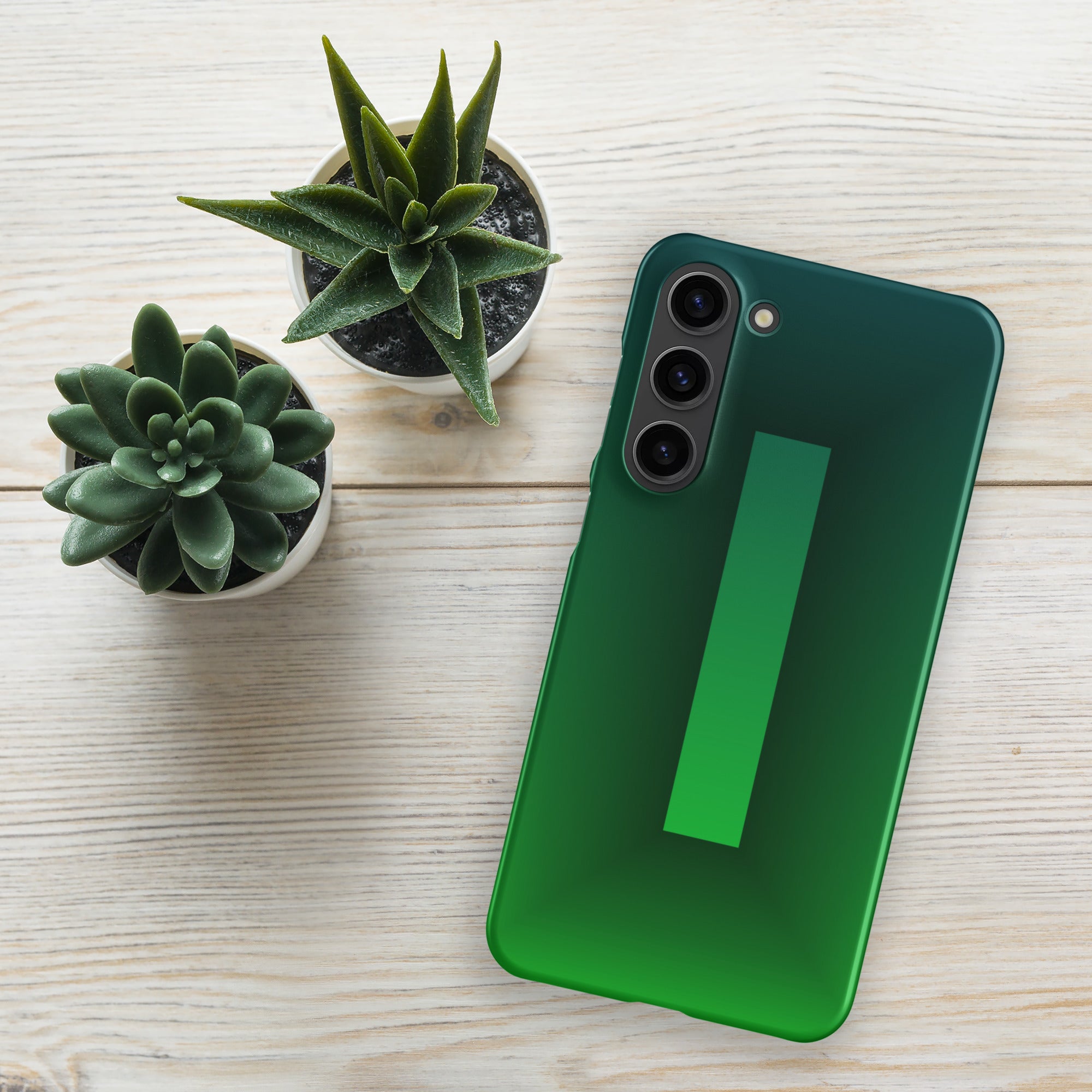 Green smartphone on a light wooden surface with two small potted plants.