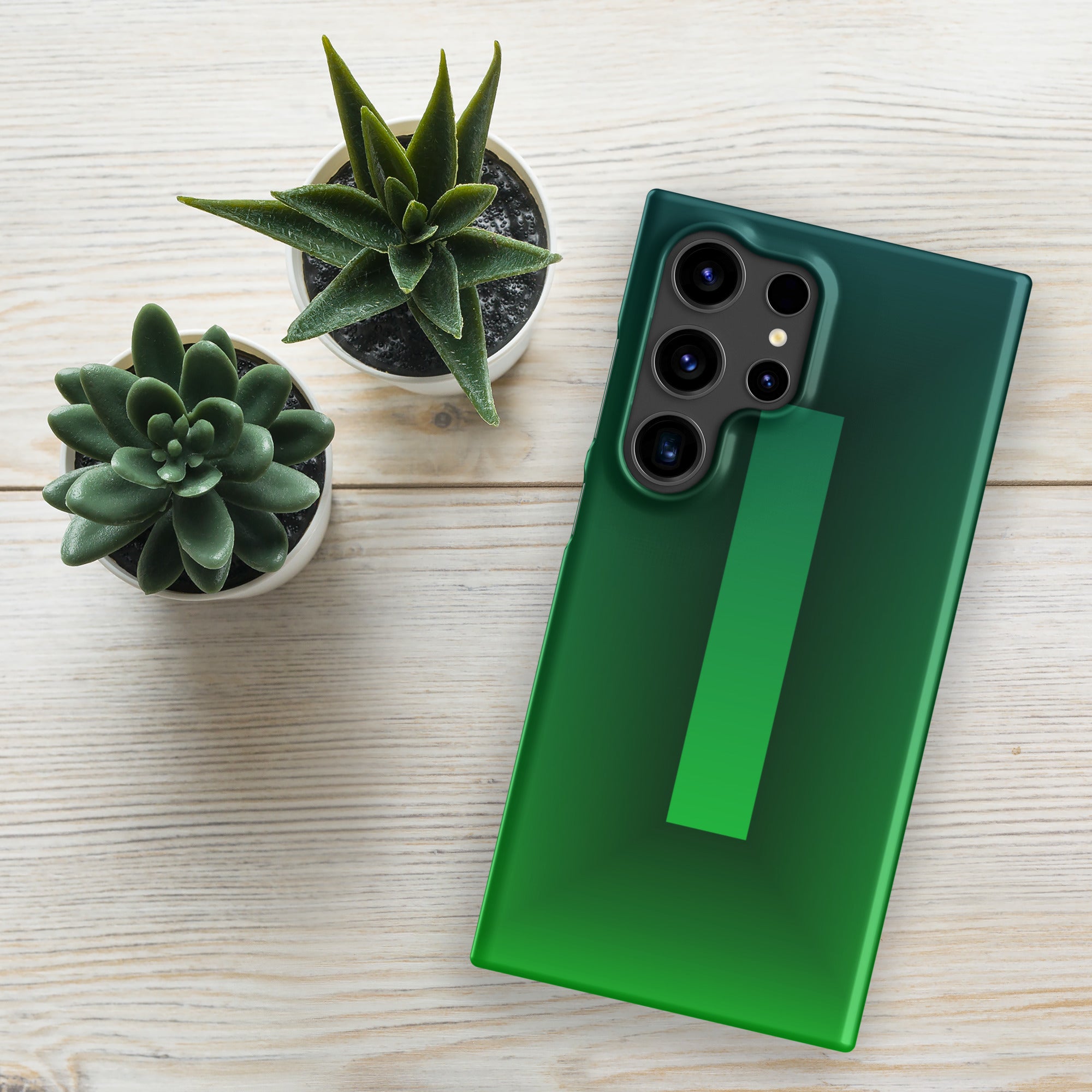 Green phone case on a green phone with two potted plants on a light wooden surface