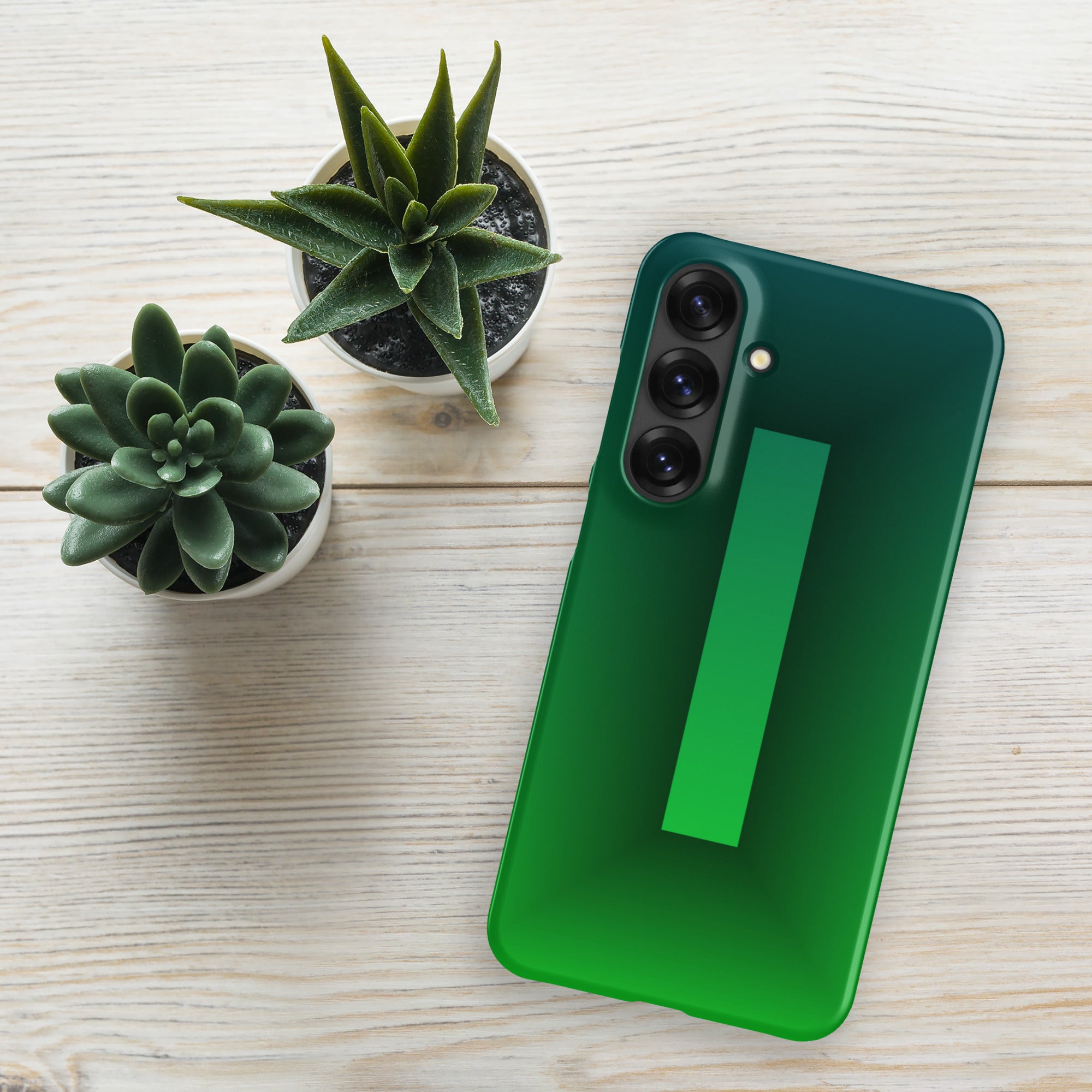 Green smartphone on a light wooden surface with two small potted plants.