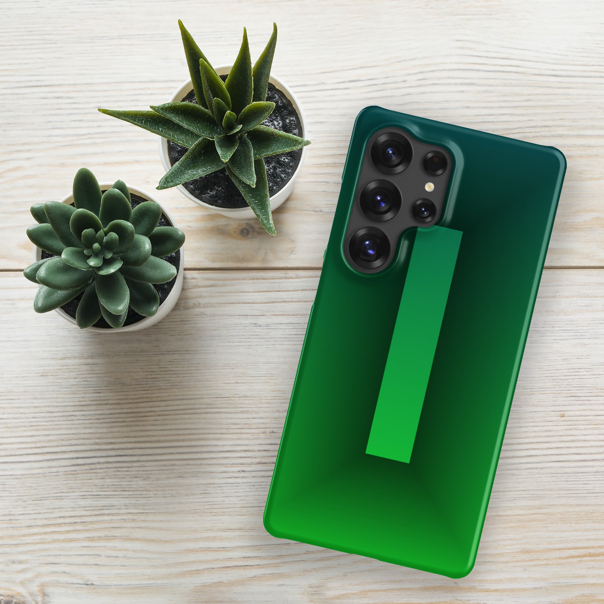 Green phone case on a green phone with two potted plants on a light wooden surface