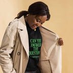 Woman wearing a black t-shirt with green text and a beige trench coat on a beige background