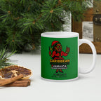 Green mug with Jamaican-themed design on a white surface with Christmas decorations.